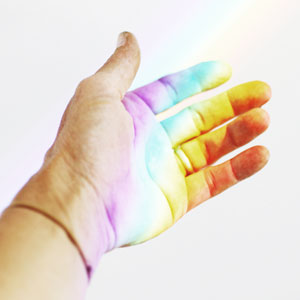licht-faellt-auf-hand-in-regenbogen-farben